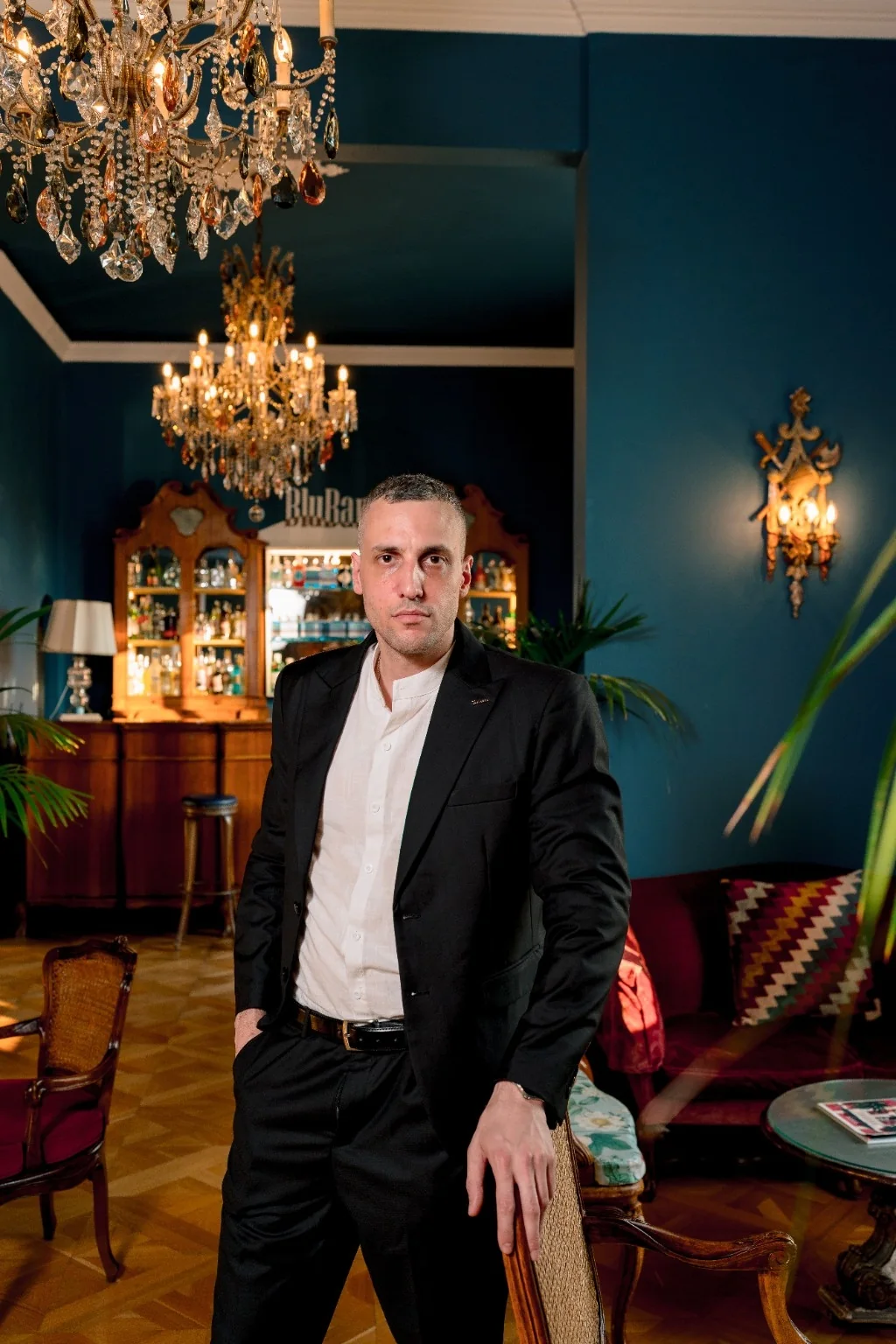 Michael in a black suit beneath a chandelier