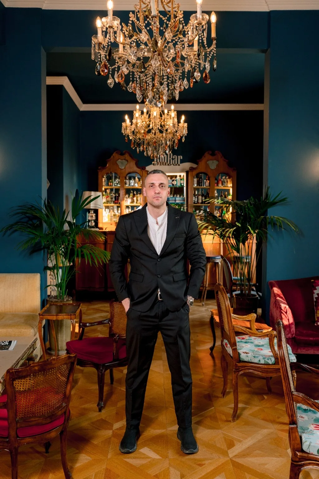 Michael standing in a full-length black suit portrait